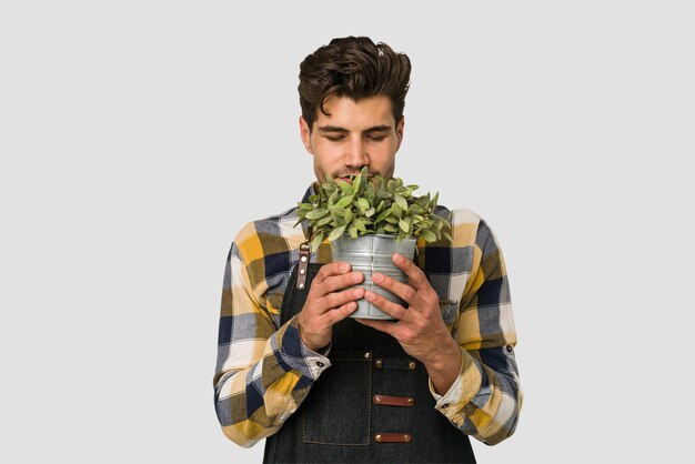 Młody kaukaski ogrodnik mężczyzna trzyma roślinę odizolowywającą na białym tle