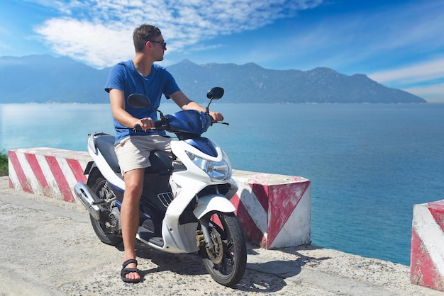 Młody kierowca motocykla siedzący i trzymający kask na morzu południowo-południowochińskim w Wietnamie