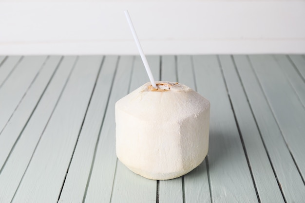 Młody kokos ze słomą na stole