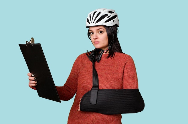 Młody kontuzjowany rowerzysta czyta raport z wypadku, nosząc bandaż podtrzymujący ramię po wypadku drogowym
