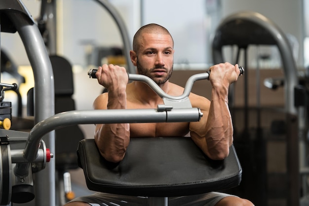 Młody kulturysta wykonujący ciężkie ćwiczenia na biceps