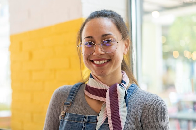 Młody łaciński Frajer Kobieta Student Uśmiecha Się Do Kamery W Pomieszczeniu W Klasie Uniwersytet Dziewczyna Z Okularami Na Tle żółtej ściany Skupić Się Na Twarzy