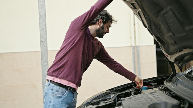 Młody Latynos naprawia samochód na ulicy