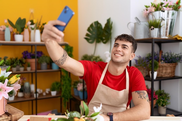 Młody latynoski kwiaciarnia robi selfie smartfonem w kwiaciarni