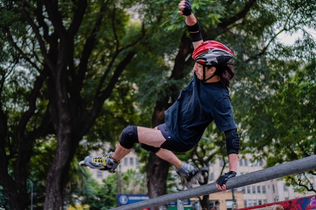 Młody latynoski mężczyzna w skateparku, skaczący z rolkami pod niskim kątem