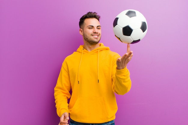 Młody latynoski mężczyzna z piłki nożnej piłką na purpurach