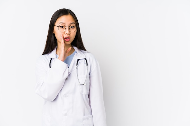 Młody lekarz Chinka na białym tle mówi tajną wiadomość o gorącym hamowaniu i patrzy na bok