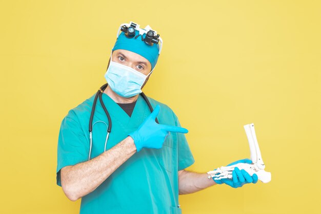 Młody lekarz chirurg ubrany na zielono na żółtym tle