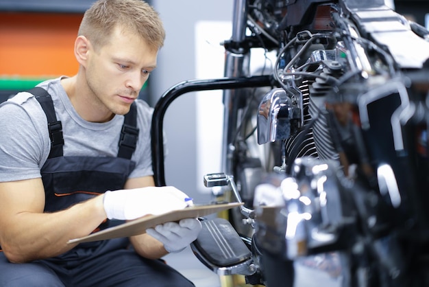 Młody mechanik samochodowy prowadzi diagnostykę silnika motocykla w serwisie samochodowym