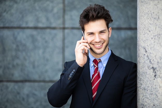 Młody menedżer na telefon na świeżym powietrzu w środowisku miejskim