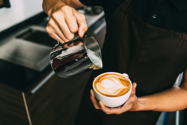 Młody Męski Barista Nalewający Gorące Mleko Do Czarnej Kawy Espresso Do Robienia Latte Art