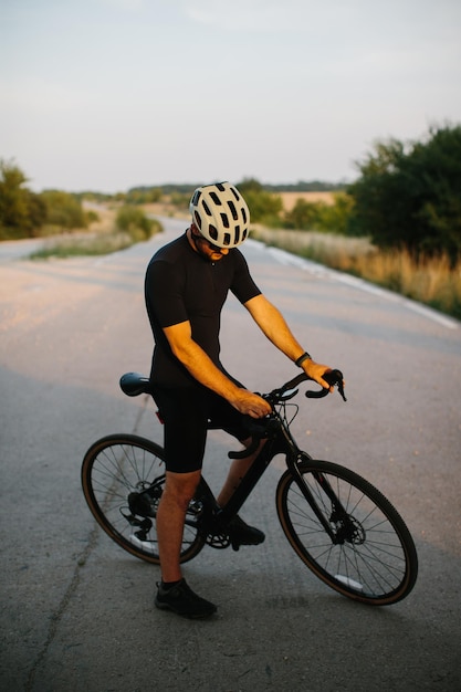 Młody męski cyklista sprawdza jego rower szosowy