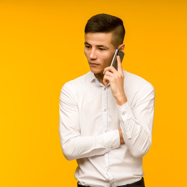 Młody mężczyzna azjatyckich biznesmen rozmawia poważnie przez telefon.