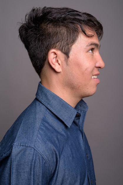 Młody mężczyzna Azji na sobie niebieską koszulę przed szarej ścianie