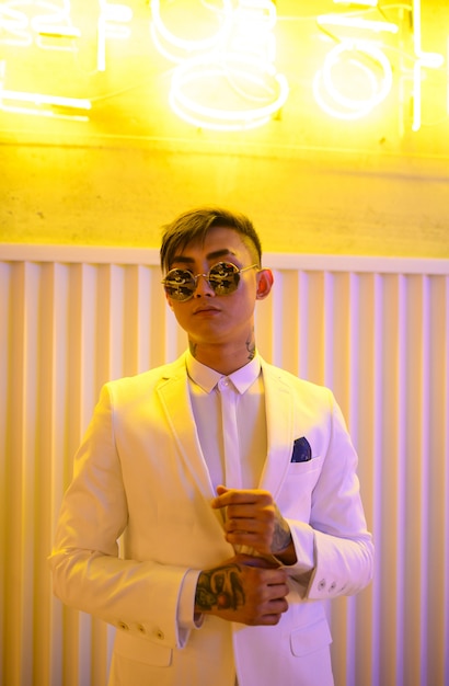 Młody Mężczyzna Azji W Białym Garniturze Na ścianie Z Neonów