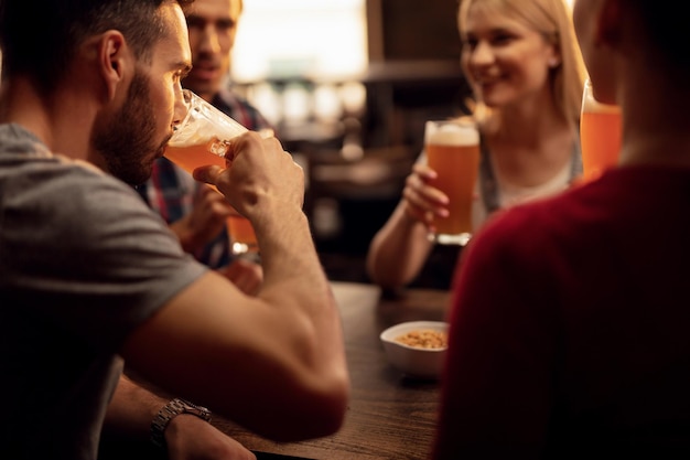 Młody mężczyzna bawi się z przyjaciółmi podczas picia piwa w barze
