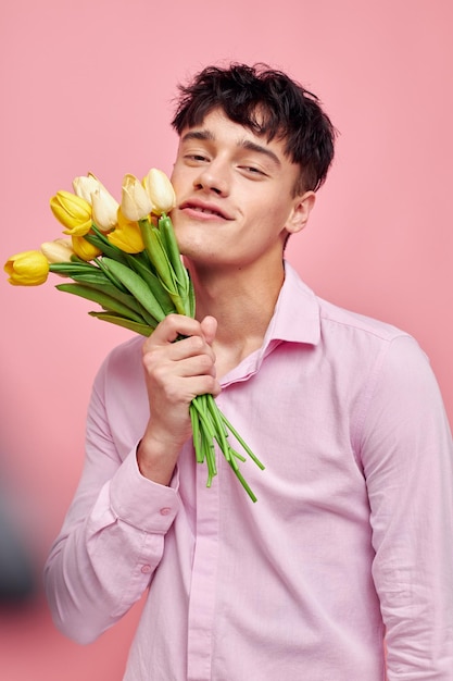 Młody mężczyzna bukiet żółtych kwiatów romans pozuje moda różowe tło niezmienione