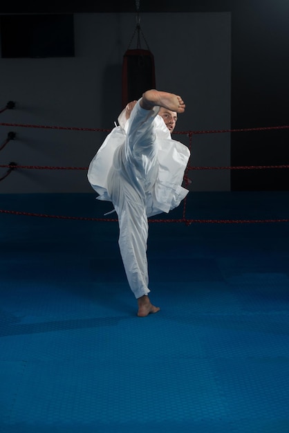 Młody mężczyzna ćwiczący swoje karate porusza białe kimono w czarnym pasie