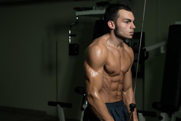 Młody mężczyzna Ćwiczenia na siłowni, które wykonuje na dwie ręce Triceps Push Down