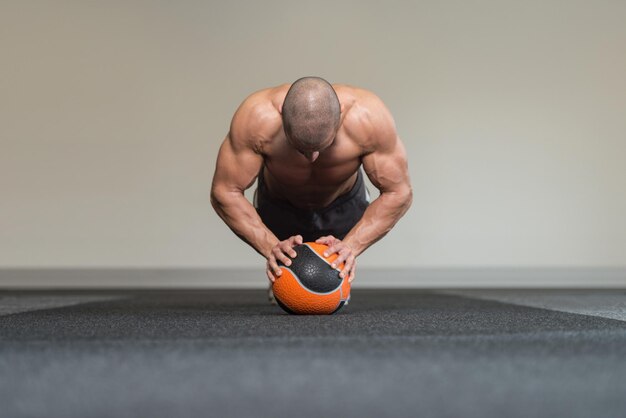 Młody mężczyzna ćwiczenie z piłką medyczną w klubie fitness