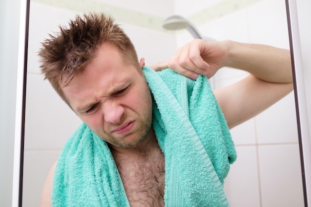 Zdjęcie młody mężczyzna czyści ucho podczas brania prysznica i stojąc pod bieżącą wodą