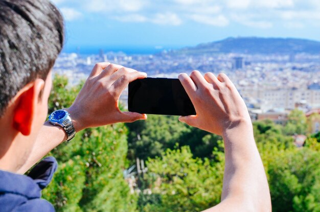 Zdjęcie młody mężczyzna fotografuje miasto za pomocą telefonu komórkowego