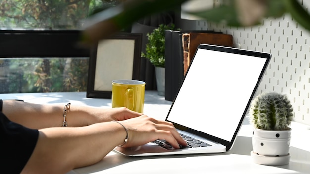 Młody mężczyzna freelancer siedzi w jasnym biurze domowym i pracuje z laptopem komputerowym