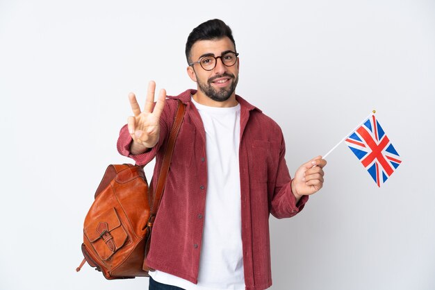 Młody mężczyzna hiszpanin trzyma flagę Zjednoczonego Królestwa szczęśliwy i liczy trzy palcami