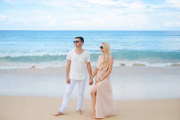 Młody mężczyzna i kobieta chodzą na tle białego piasku i lazurowego morza