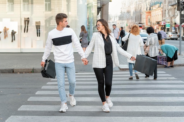 Młody mężczyzna i kobieta idący razem przez ulicę po zakupach Para z czarnymi torbami z zakupami
