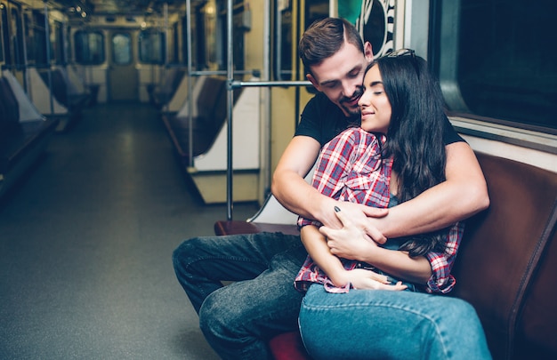 Młody Mężczyzna I Kobieta Korzystają Z Podziemia. Para W Metrze. Siedząc Na ławce I Przytulaj Się. Szczęście I Miłość.