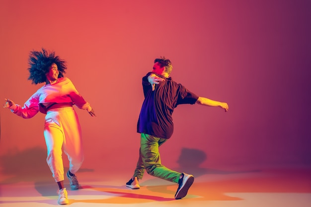 Młody Mężczyzna I Kobieta Tańczą Hip-hop W Jasnych Ubraniach Na Gradientowym Tle