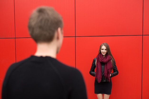 Młody mężczyzna i kobieta w pasji, emocji, na ulicy na tle czerwonej ściany. Moda