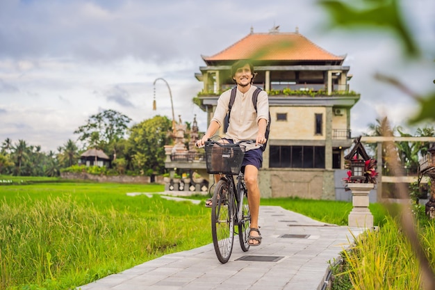 Młody mężczyzna jeździ na rowerze na polu ryżowym w koncepcji podróży ubud bali bali