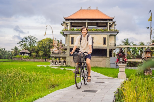 Młody mężczyzna jeździ na rowerze na polu ryżowym w koncepcji podróży ubud bali bali