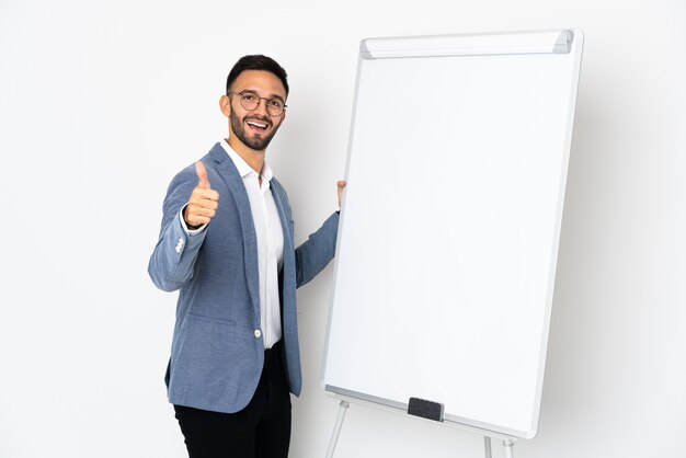 Młody mężczyzna kaukaski na białym tle dając prezentację na tablicy z kciukiem do góry