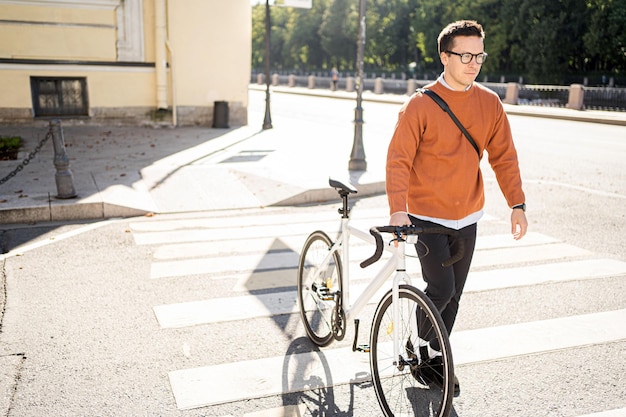 Młody mężczyzna na biznesowym rowerze jedzie do pracy w miejskim transporcie ekologicznym