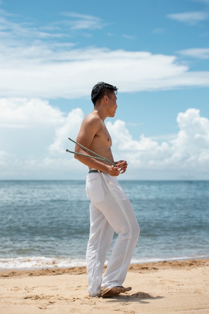 Zdjęcie młody mężczyzna na plaży przygotowuje się do ćwiczeń capoeira