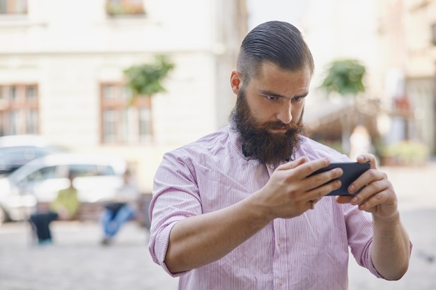 Młody mężczyzna na zewnątrz patrzący na swój telefon komórkowy