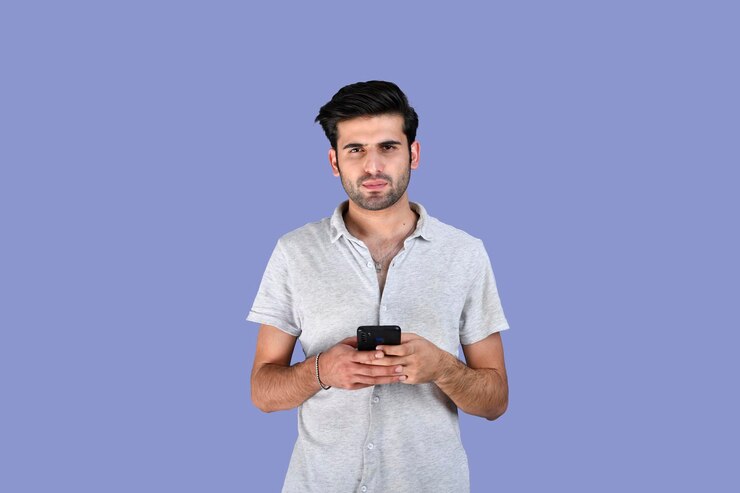 Młody mężczyzna noszący letnie ubrania przy użyciu telefonu komórkowego wygląda infront indyjskiego pakistańskiego modelu
