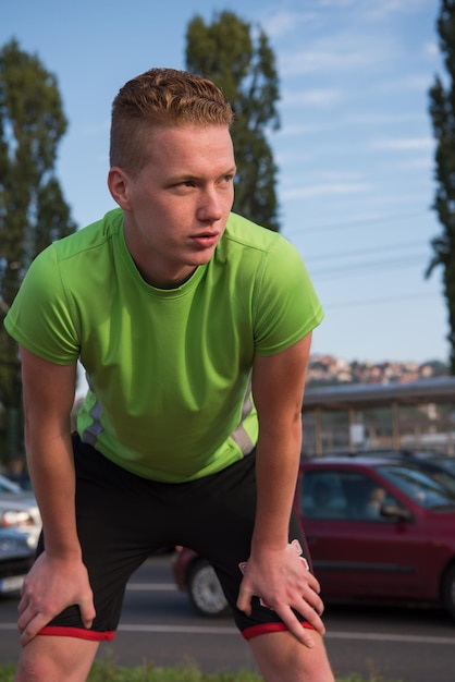 Młody mężczyzna patrzy na resztę ścieżki podczas przerwy w treningu joggingu na świeżym powietrzu
