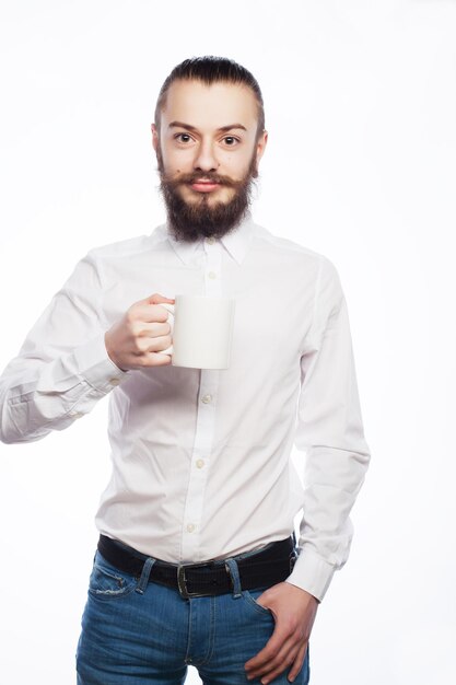 Młody mężczyzna pijący filiżankę kawy lub herbaty na białym tle