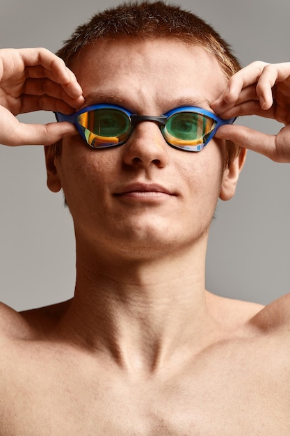 Młody mężczyzna pływak przygotowuje się do startu zbliżenie portret pływaka w masce i kapeluszu szarym tle kopia koncepcja pływania przestrzeni