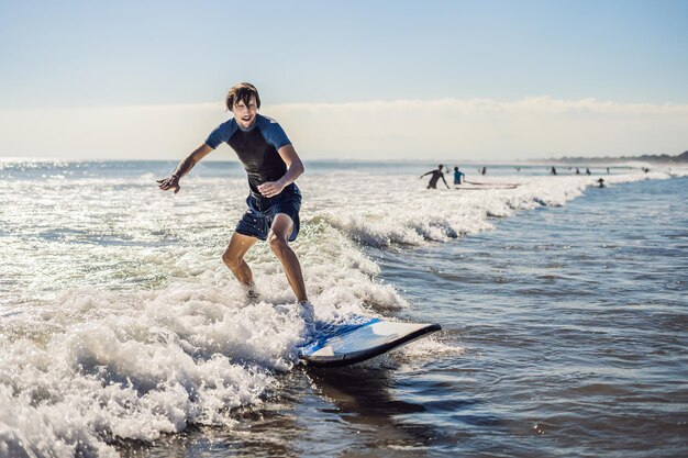 Młody mężczyzna, początkujący Surfer uczy się surfować na morskiej pianie na wyspie Bali