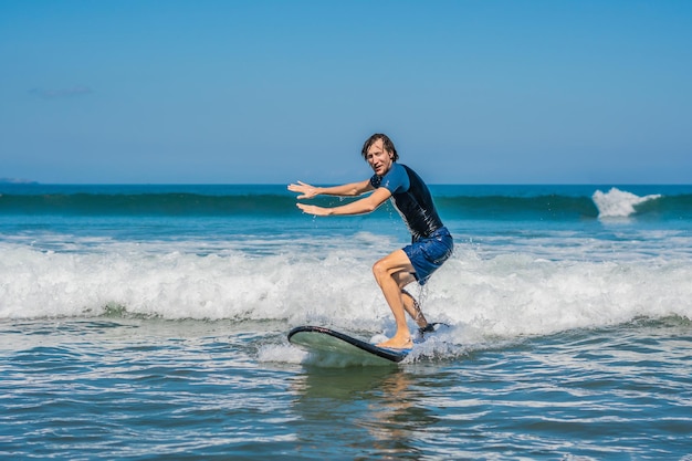 Młody Mężczyzna, Początkujący Surfer Uczy Się Surfować Na Morskiej Pianie Na Wyspie Bali