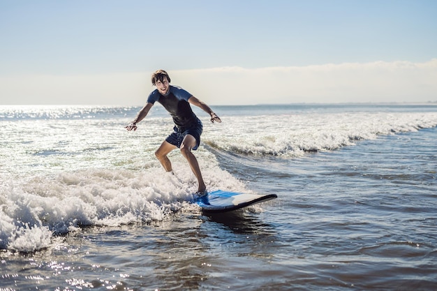 Młody mężczyzna, początkujący Surfer uczy się surfować na morskiej pianie na wyspie Bali