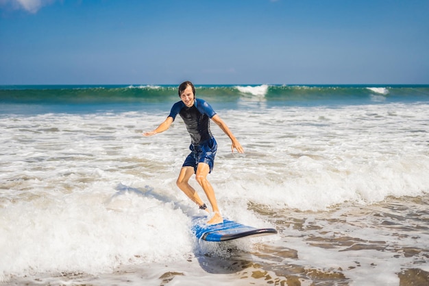 Młody mężczyzna, początkujący Surfer uczy się surfować na morskiej pianie na wyspie Bali