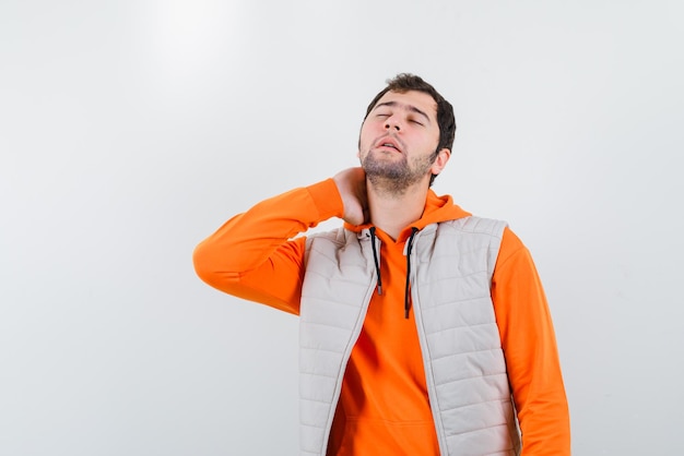 Młody mężczyzna pokazujący ból szyi na białym tle