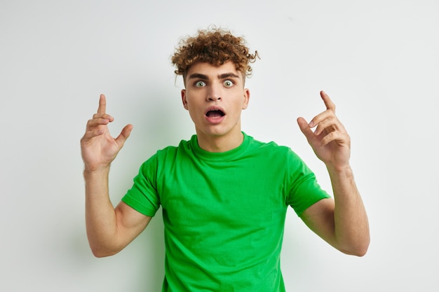 Młody mężczyzna pozuje na białym tle w zielonej koszulce
