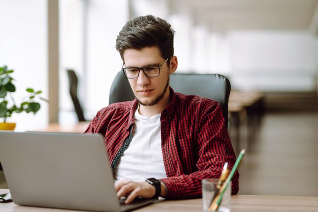 Młody mężczyzna pracujący na laptopie Edukacja i praca online Praca zdalna Freelancer technologii